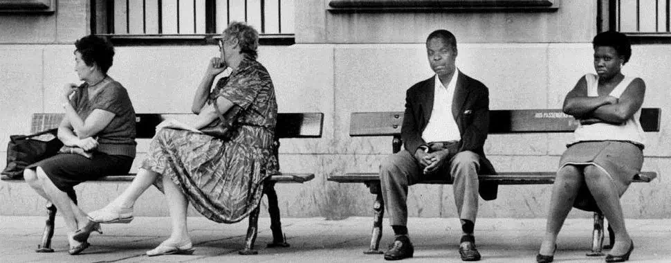 Foto em que é demonstrado como era a segregação na África do Sul à época do apartheid: banco reservado à pessoas negras e outro à pessoas brancas. Na foto é possível observar as duas mulheres brancas sentadas de costas para um homem negro e uma mulher negra. Texto: Direitos civis: afinal, o que são e como surgiram?