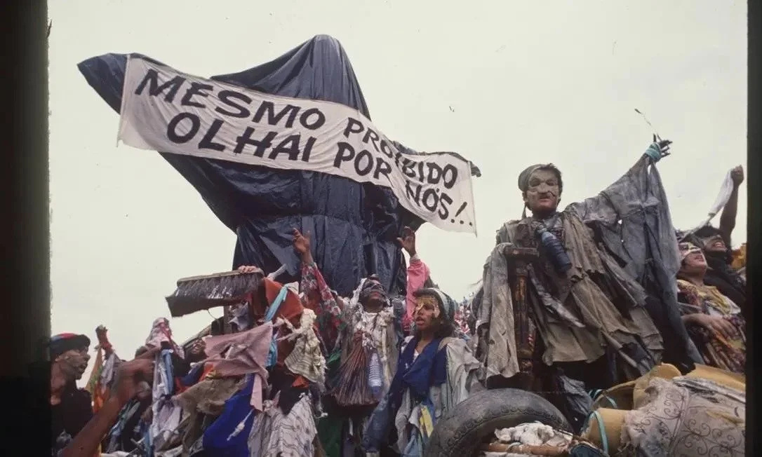 Desfile da Beija-Flor de Nilópolis, 1989 Faixa de desfile escrito "mesmo proibido, olhai por nós"