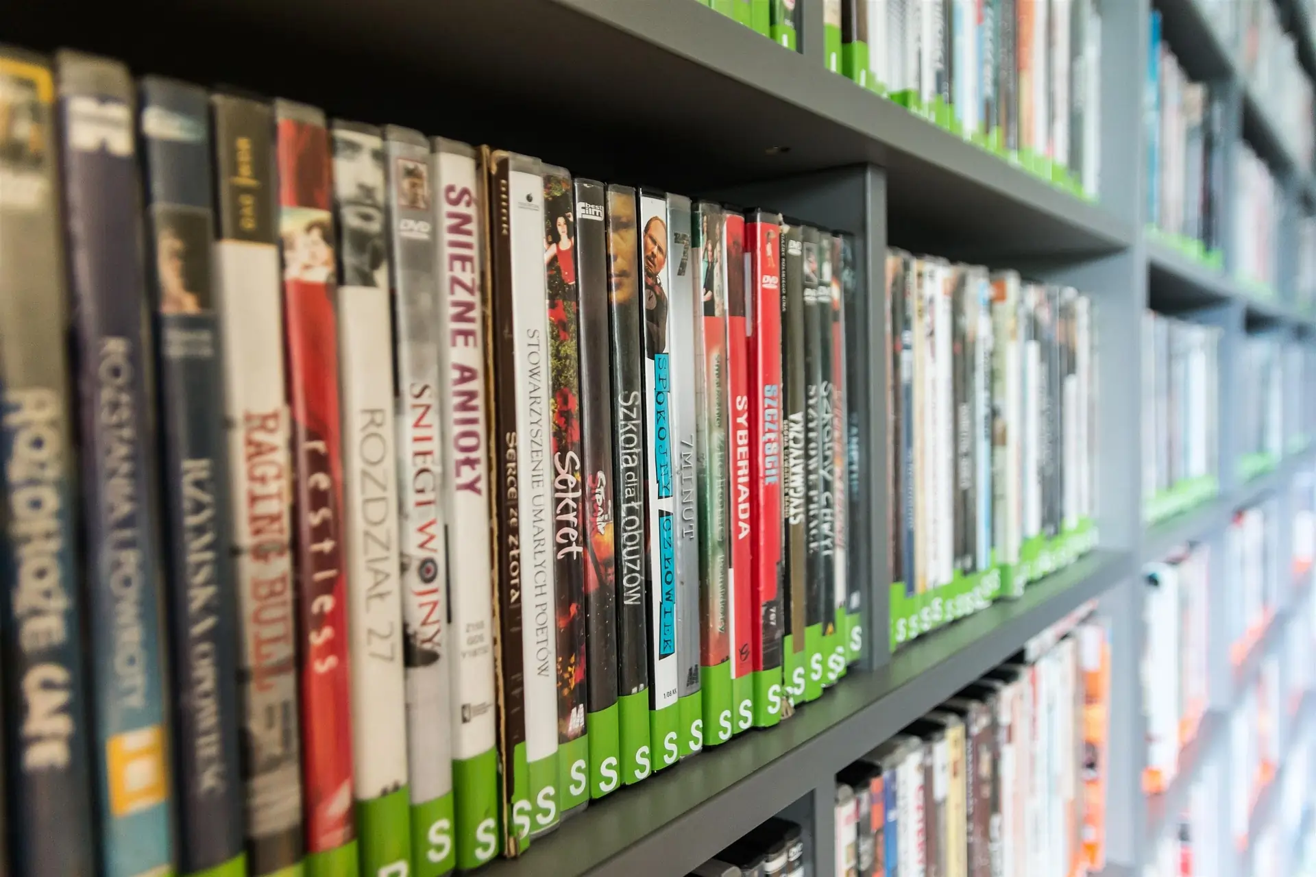 Streaming representou a evolução de diversos serviços, como a locação de filmes. Estante de capas de DVDs enfileirados em locadora de filmes.