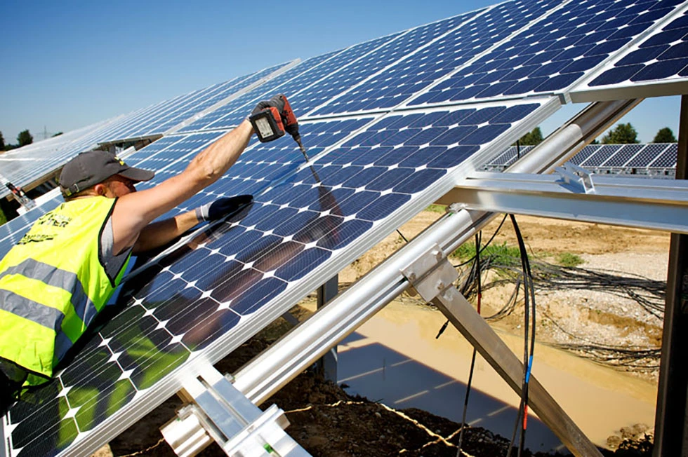 Foto de um homem instalando um painel solar para representar a ampliação da energia renovável no país