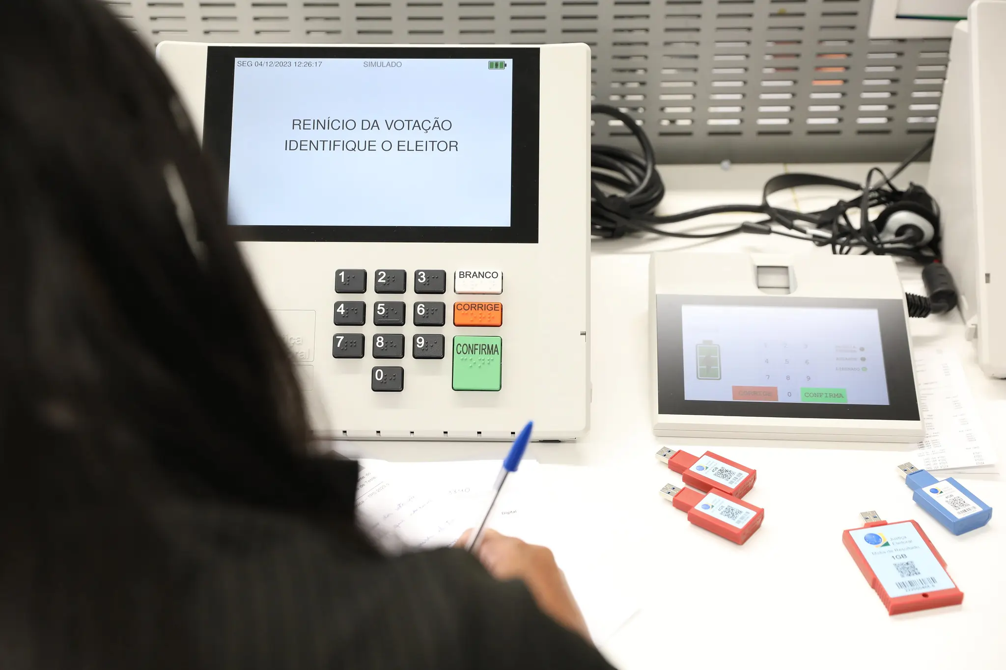 Funcionária da Justiça Eleitoral realizando testes em uma urna eletrônica.