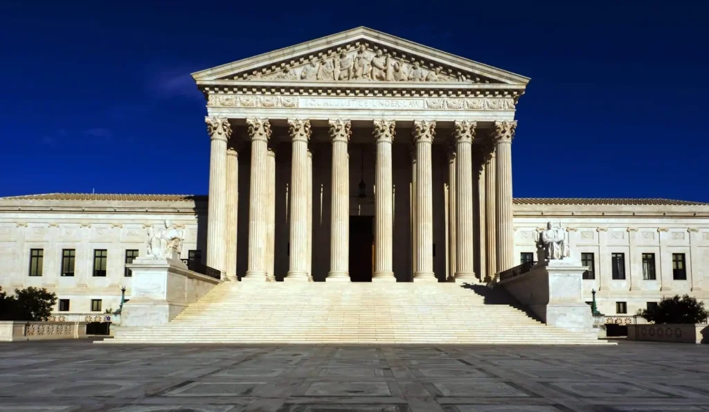 Na imagem, a estrutura da Suprema Corte dos Estados Unidos, que faz uma releitura da arquitetura grega, com pilares gigantes e um teto triangular. Texto: Como funcionam as Supremas Cortes pelo mundo?
