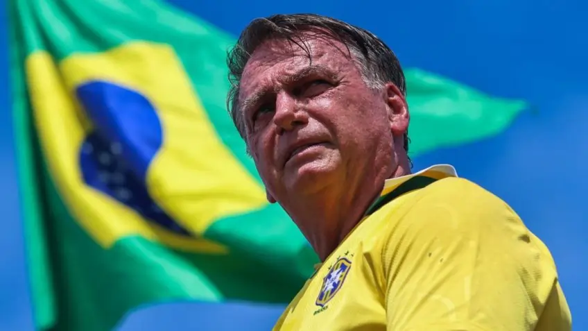 Na imagem, Bolsonaro usando blusa que remete ao Brasil, e ao fundo, a bandeira brasileira tremulando. Texto sobre o STF ter tornado Bolsonaro réu.