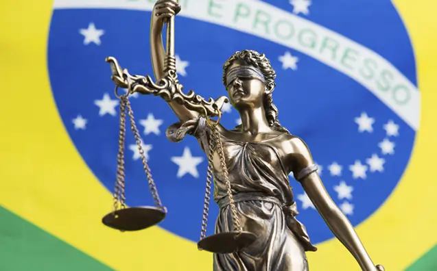 Imagem do símbolo da justiça, uma mulher vendada segurando uma balança, com a bandeira do Brasil ao fundo. Texto: O que é a abolição do Estado Democrático de Direito?