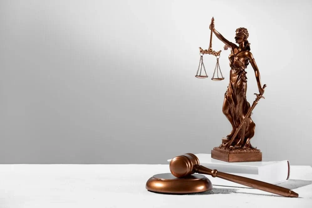 A imagem retrata a estátua da Justiça, segurando uma balança, com venda nos olhos e uma espada, simbolizando os valores centrais do curso de Direito.