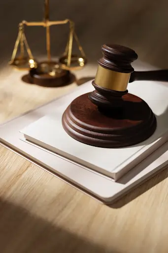 Martelo de juiz sobre um livro branco, com uma balança da justiça desfocada ao fundo, simbolizando o sistema judiciário. Texto sobre medidas cautelares.