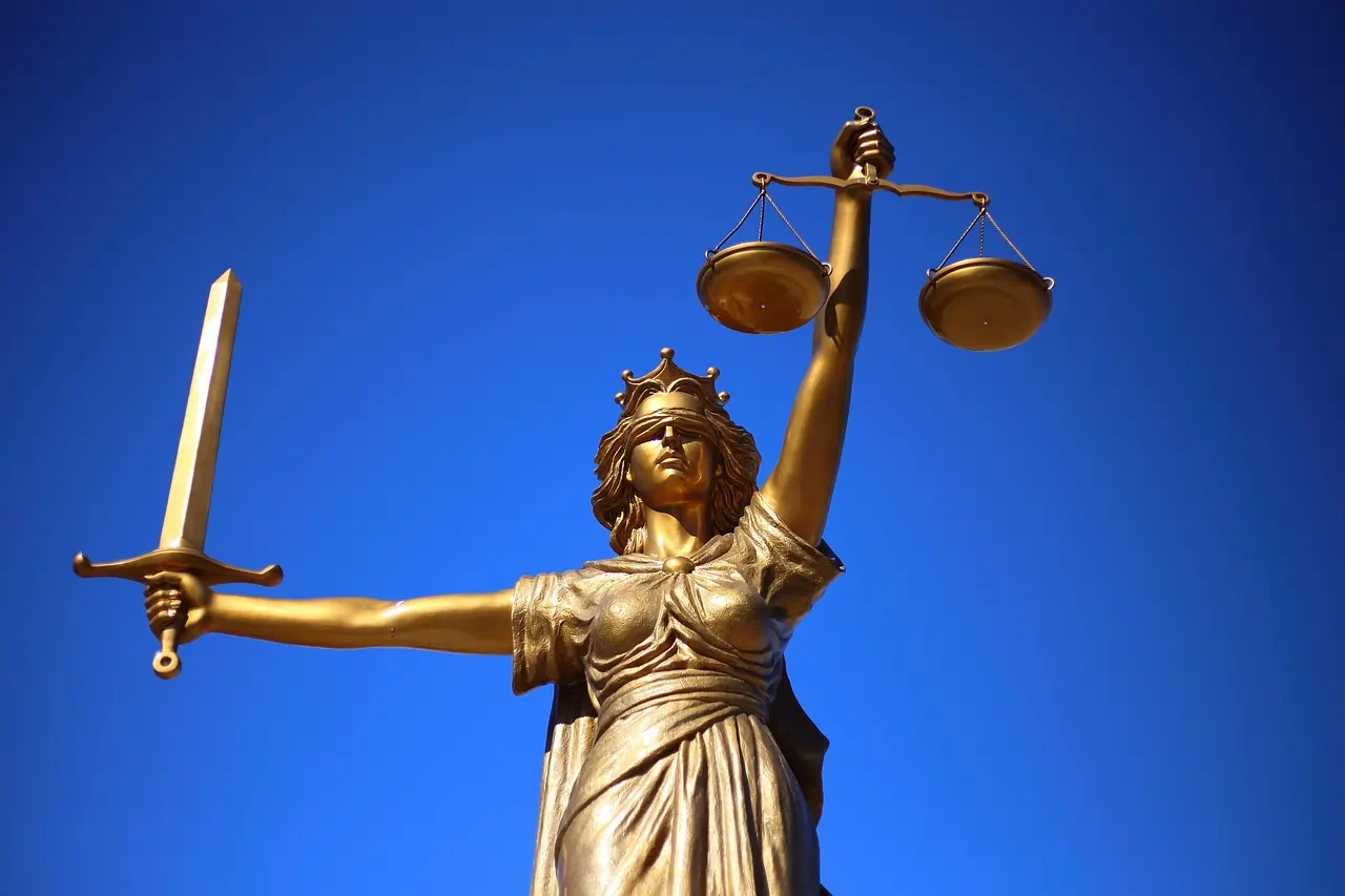 Estátua de uma mulher segurando uma espada, uma balança e com os olhos vendados, simbolizando justiça.