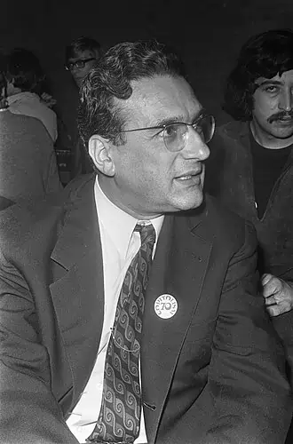 Imagem de um homem sentado, de óculos e terno, olhando para o lado. Texto: Você conhece o capitalismo tardio e a era do cansaço?
