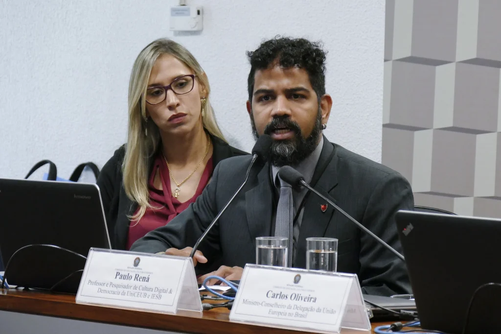 Dois profissionais, uma mulher e um homem, participam de mesa de debate.
